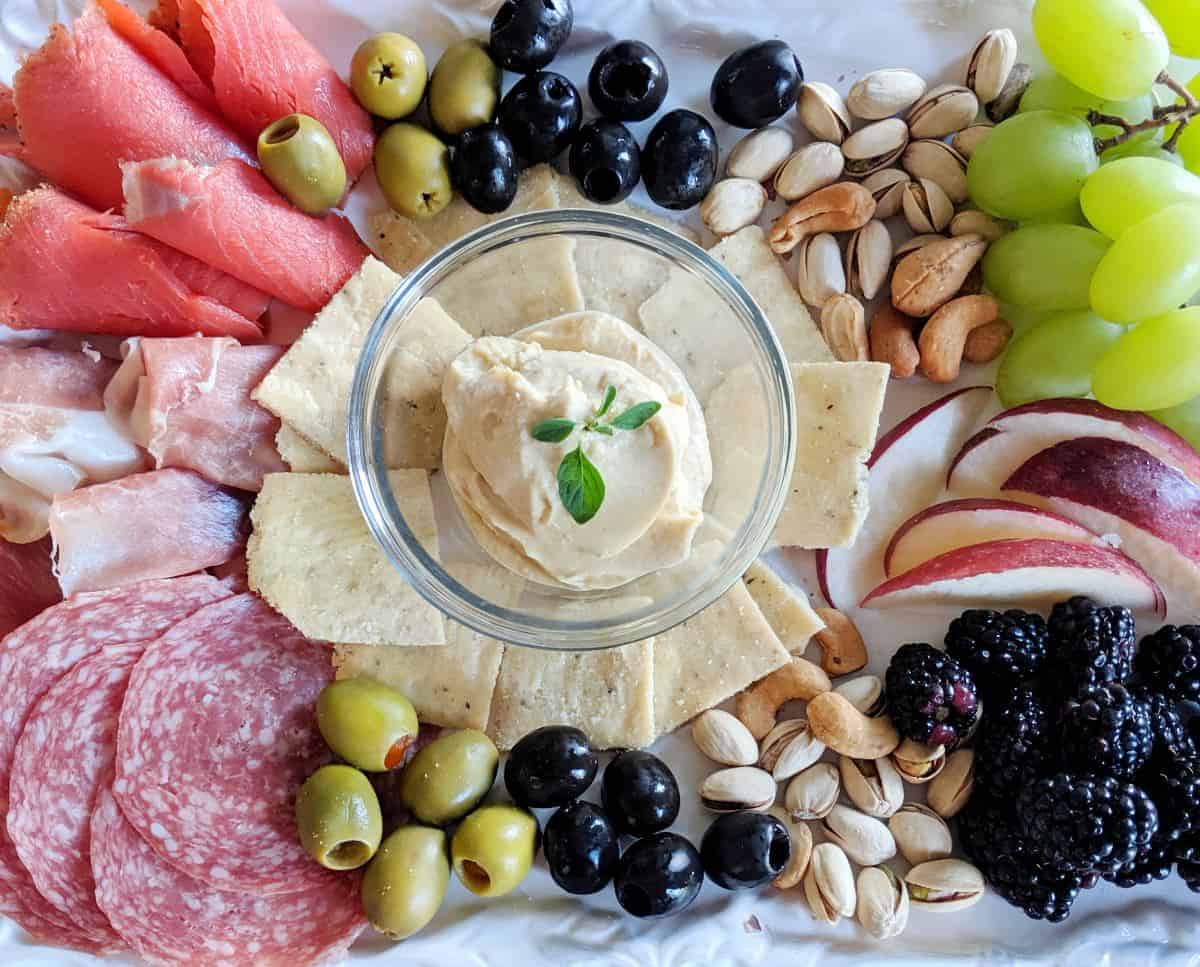 Cassava crackers on an antipasto platter filled with salami, smoked salmon, olives, hummus, grapes, nuts, etc.
