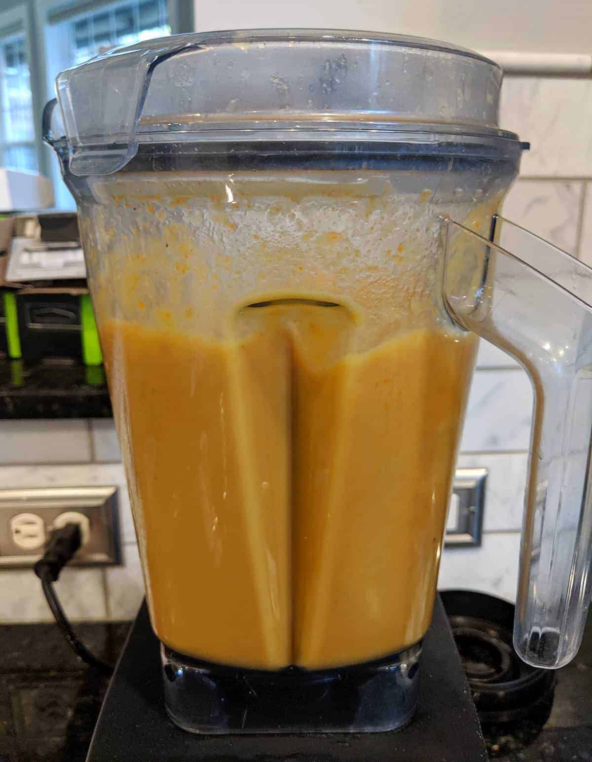 Side view of bone broth being blended with veggies.