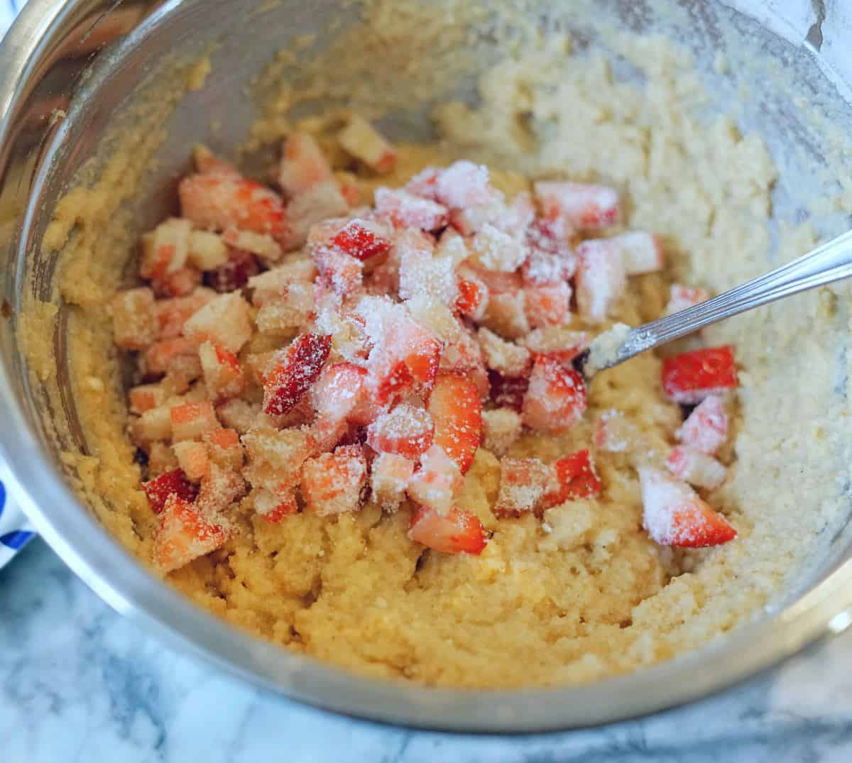 diced strawberries in a metal bowl with the muffin batter.