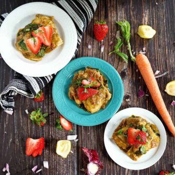 3 plates of strawberry basil chicken on a wooden table with strawberry tops, lemon peels, and basil laying around them