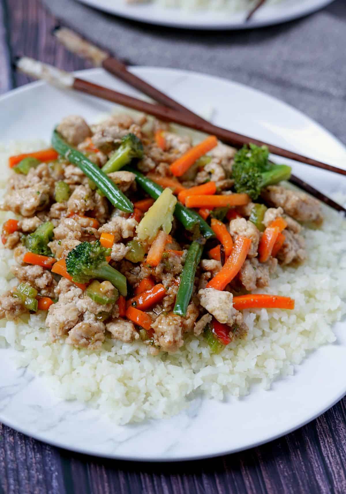 Plate of ground chicken stir fry on a towel with chopsticks.