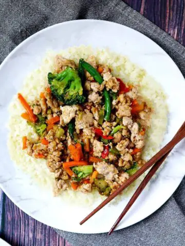 Plate of ground chicken stir fry on a towel with chopsticks.