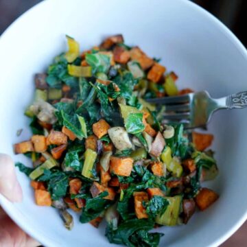 Rainbow chard, sweet potatoes, and mushrooms in a white bowl with a fork.