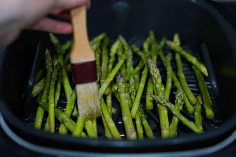 brushing oil on ninja foodi asparagus