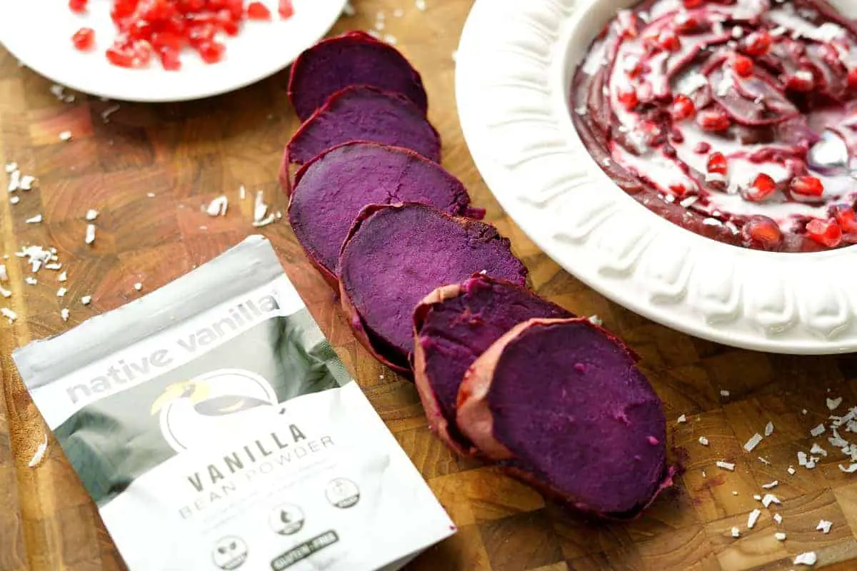 sliced purple sweet potatoes next to a purple sweet potato bowl and pack of vanilla powder.