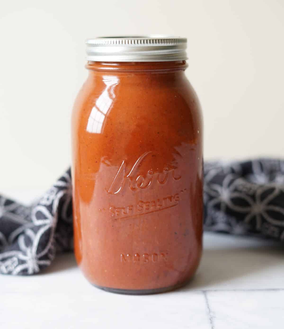 Nomato sauce in a mason jar with a black towel behind it.