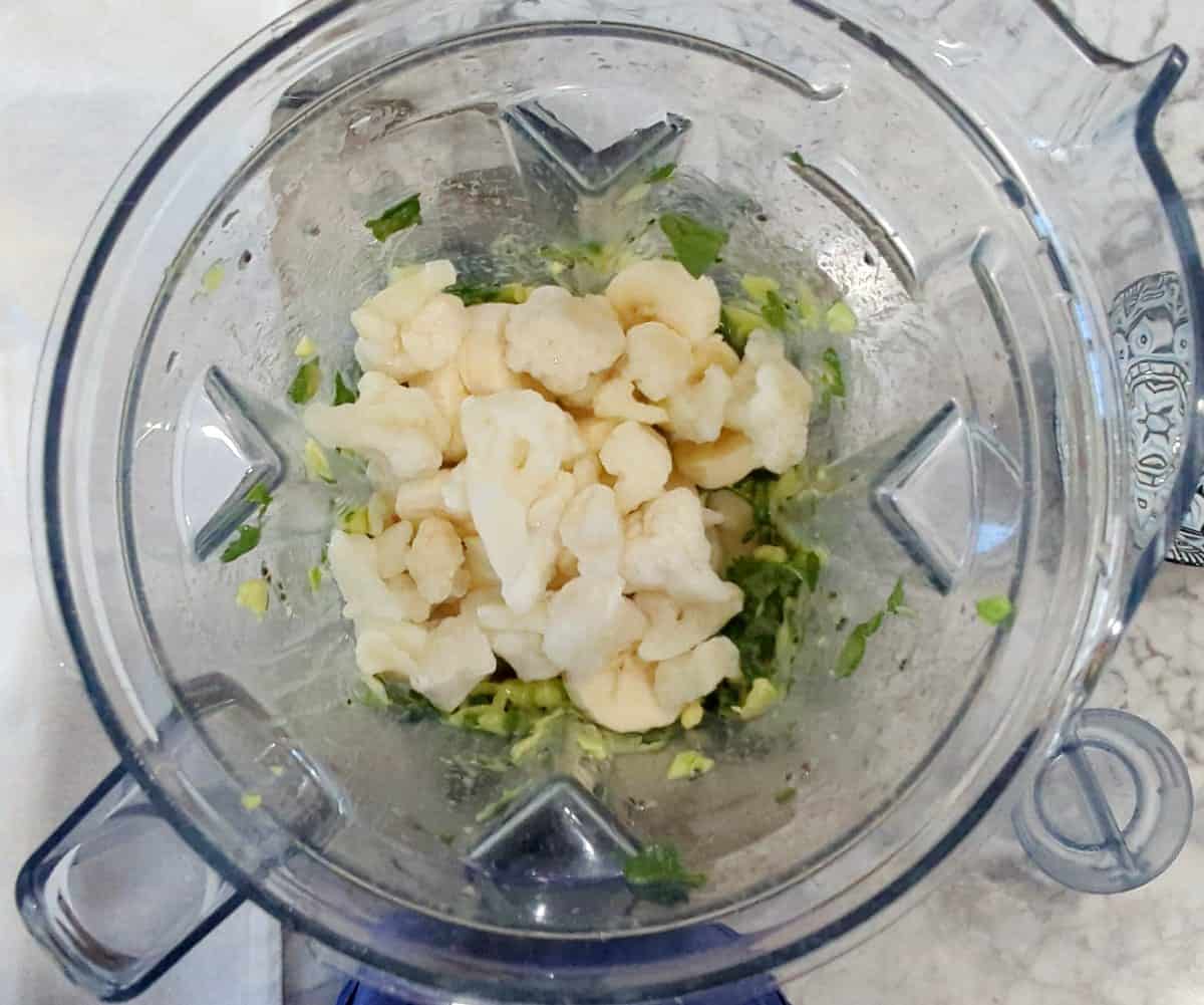 Avocado, spinach, and cauliflower in blender before blending.