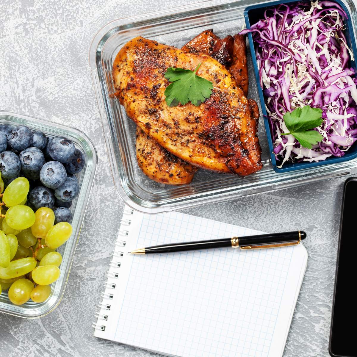Pen and pad near prepped chicken, shredded cabbage and fruit.
