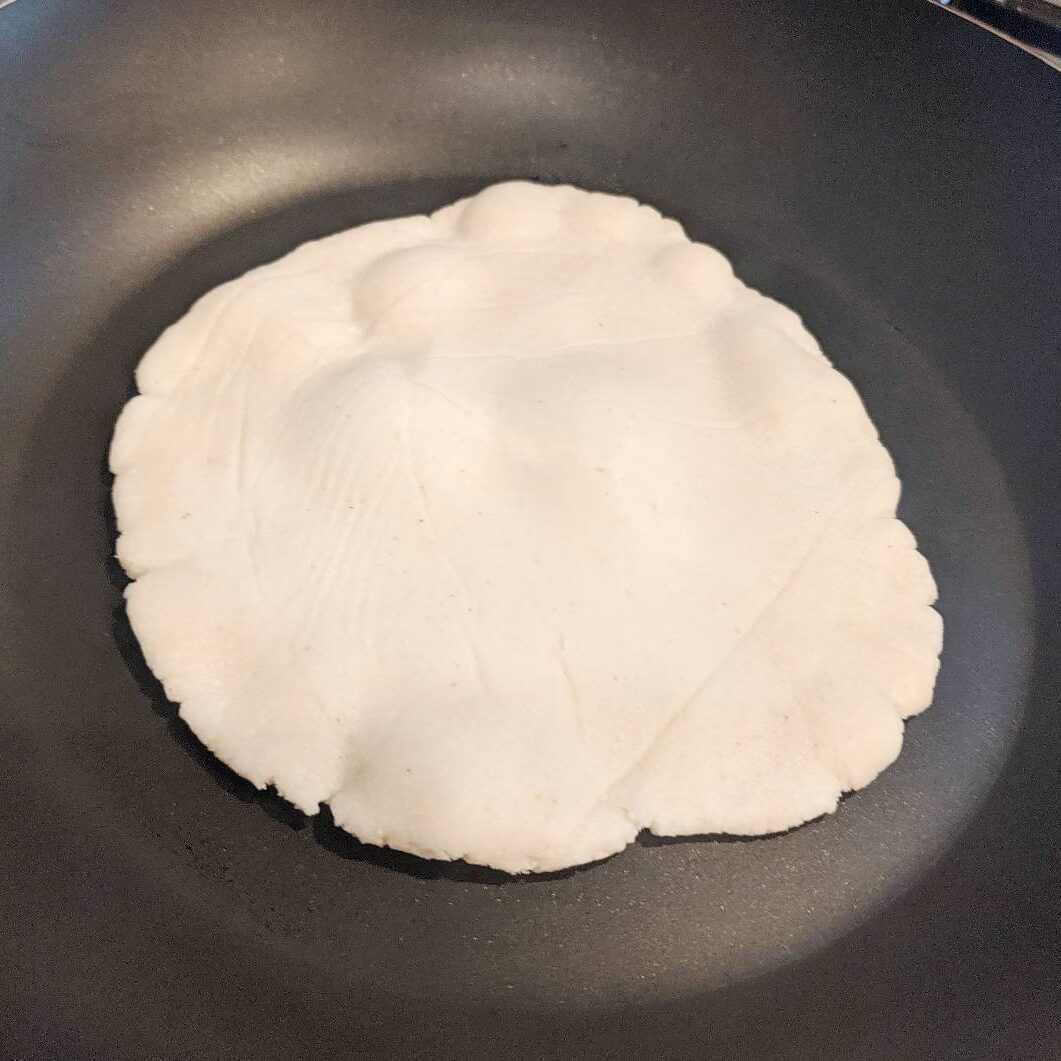 paleo tortilla in nonstick pan cooking and starting tu bubble